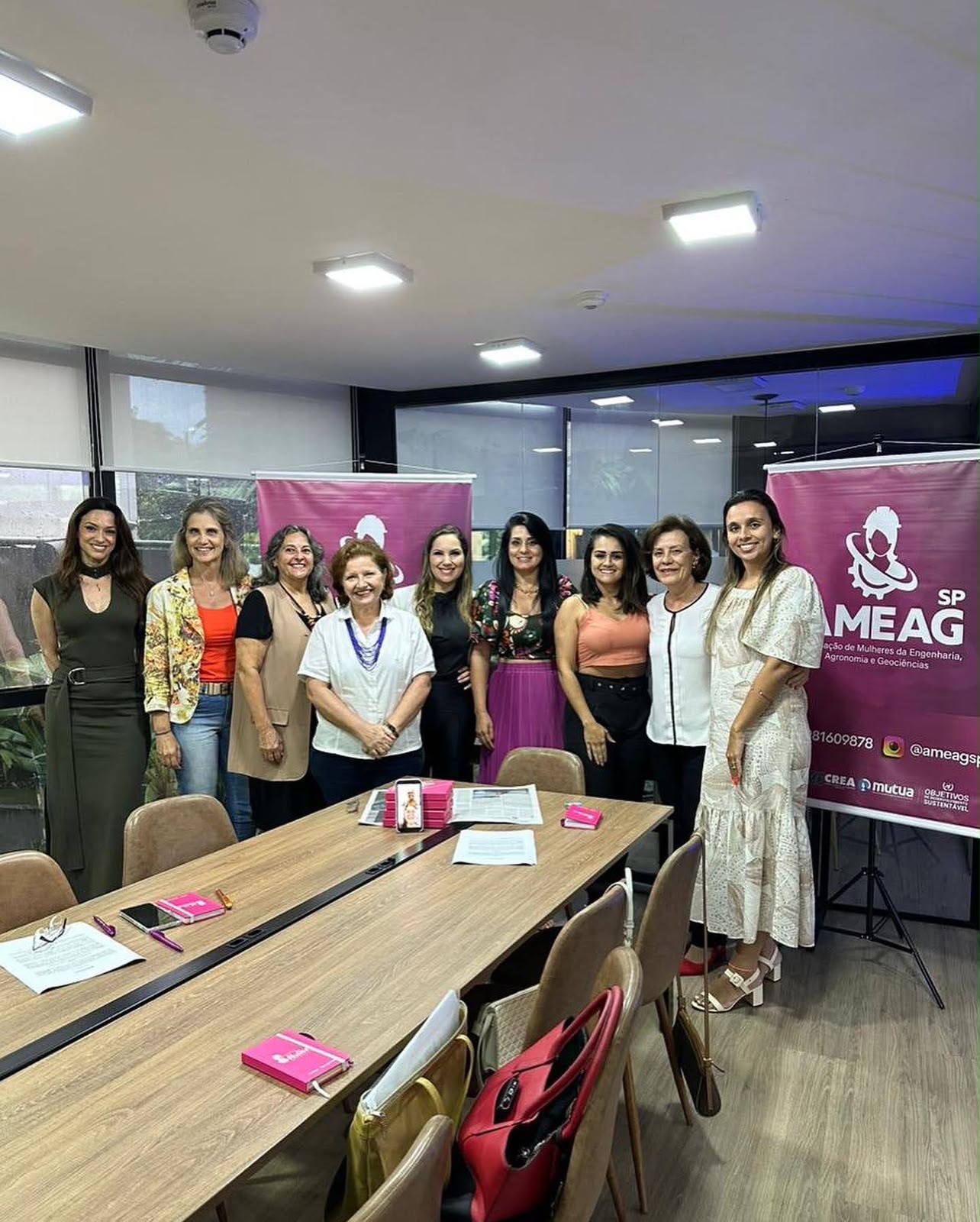 Associadas da AMEAG SP reunidas em frente aos banners da associação